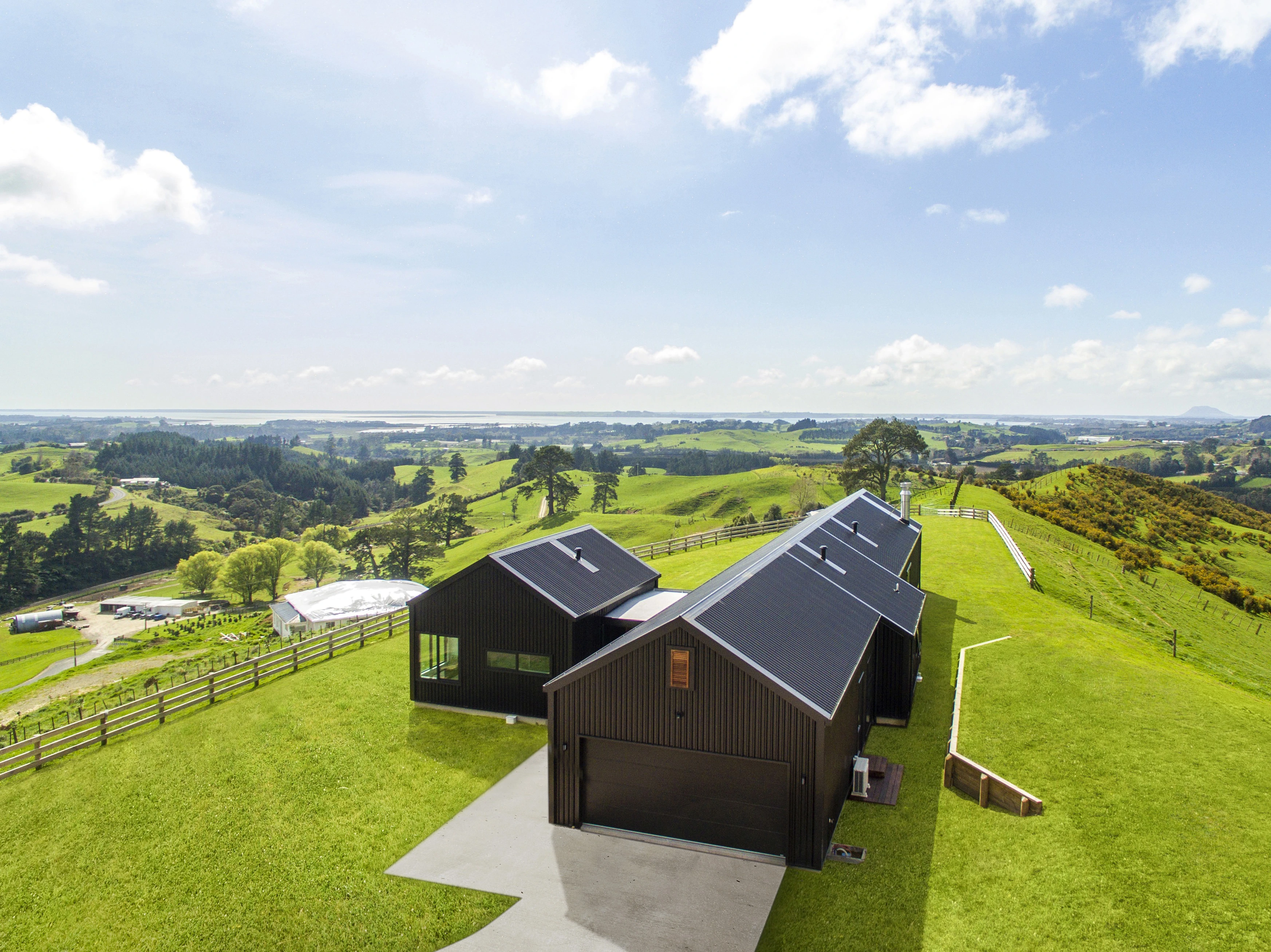 Aerial view of 4 modern houses, each with a new roof standing in a green meadow