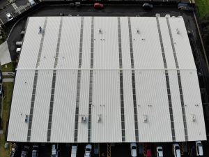 An aerial image of the new roof on a large commercial building, with cars parked around the building