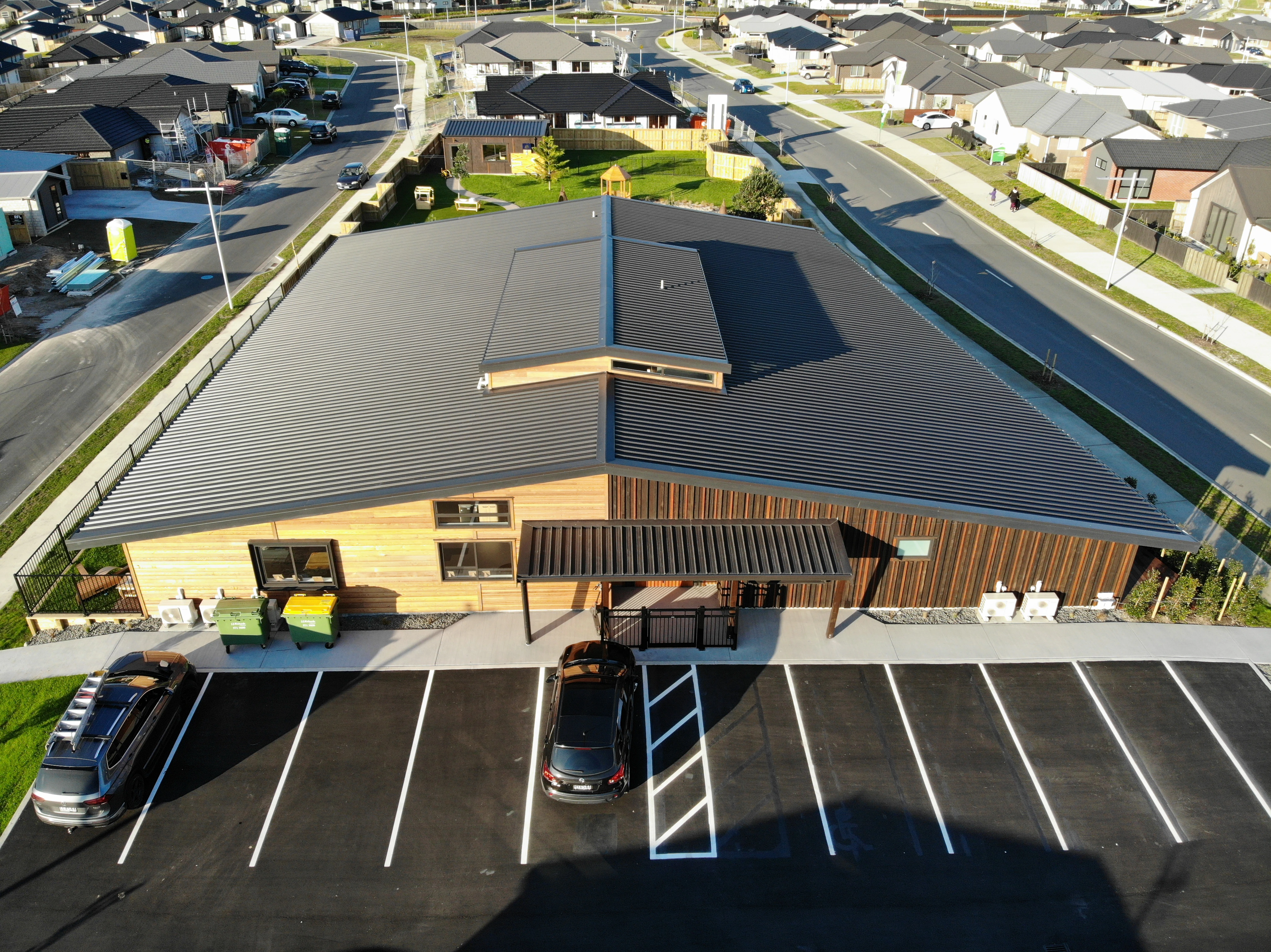 An aerial photo from distance of a commercial building with a new roof and with car parks in front