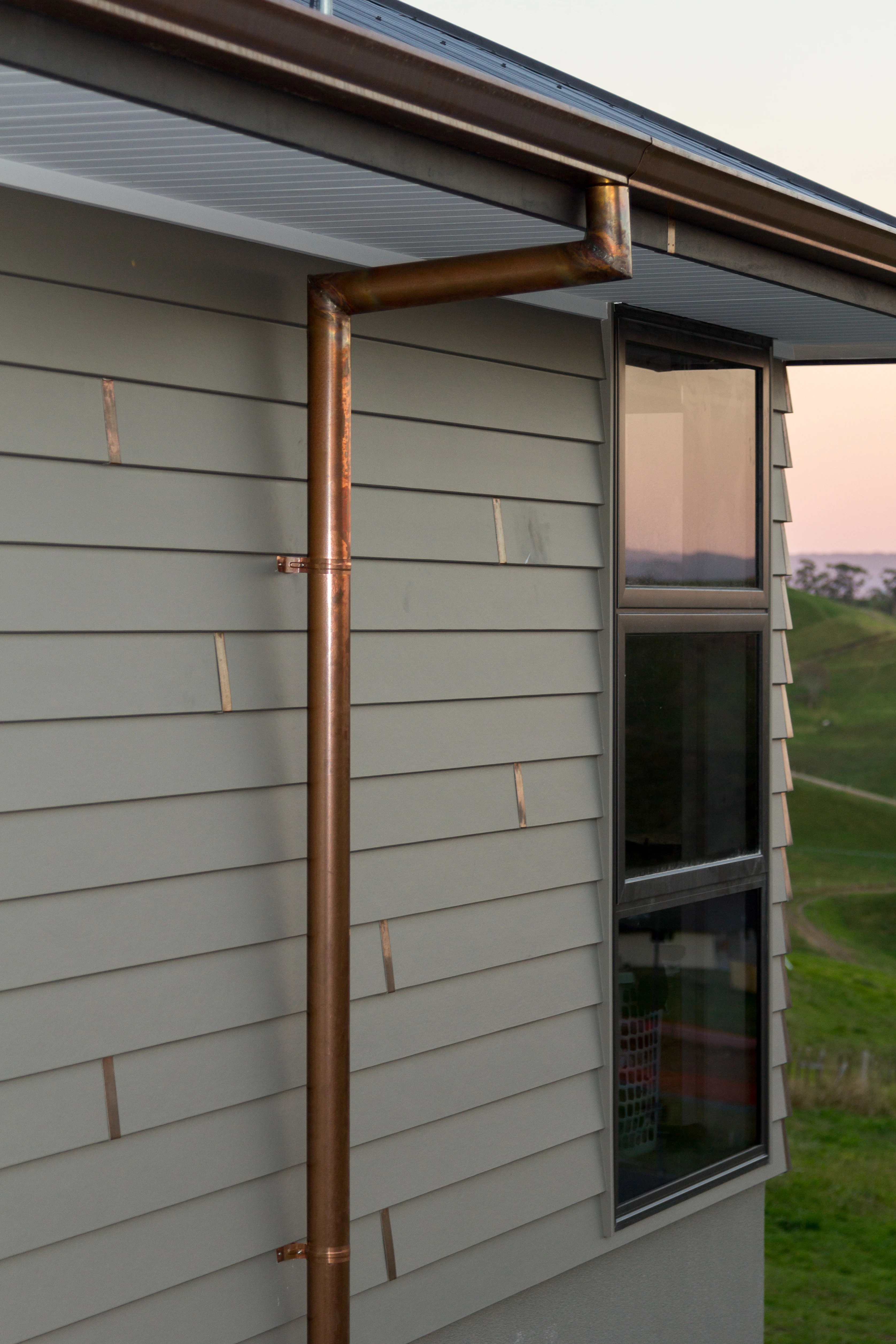 The side of a new home set in a rural area, with some of the new roof in view