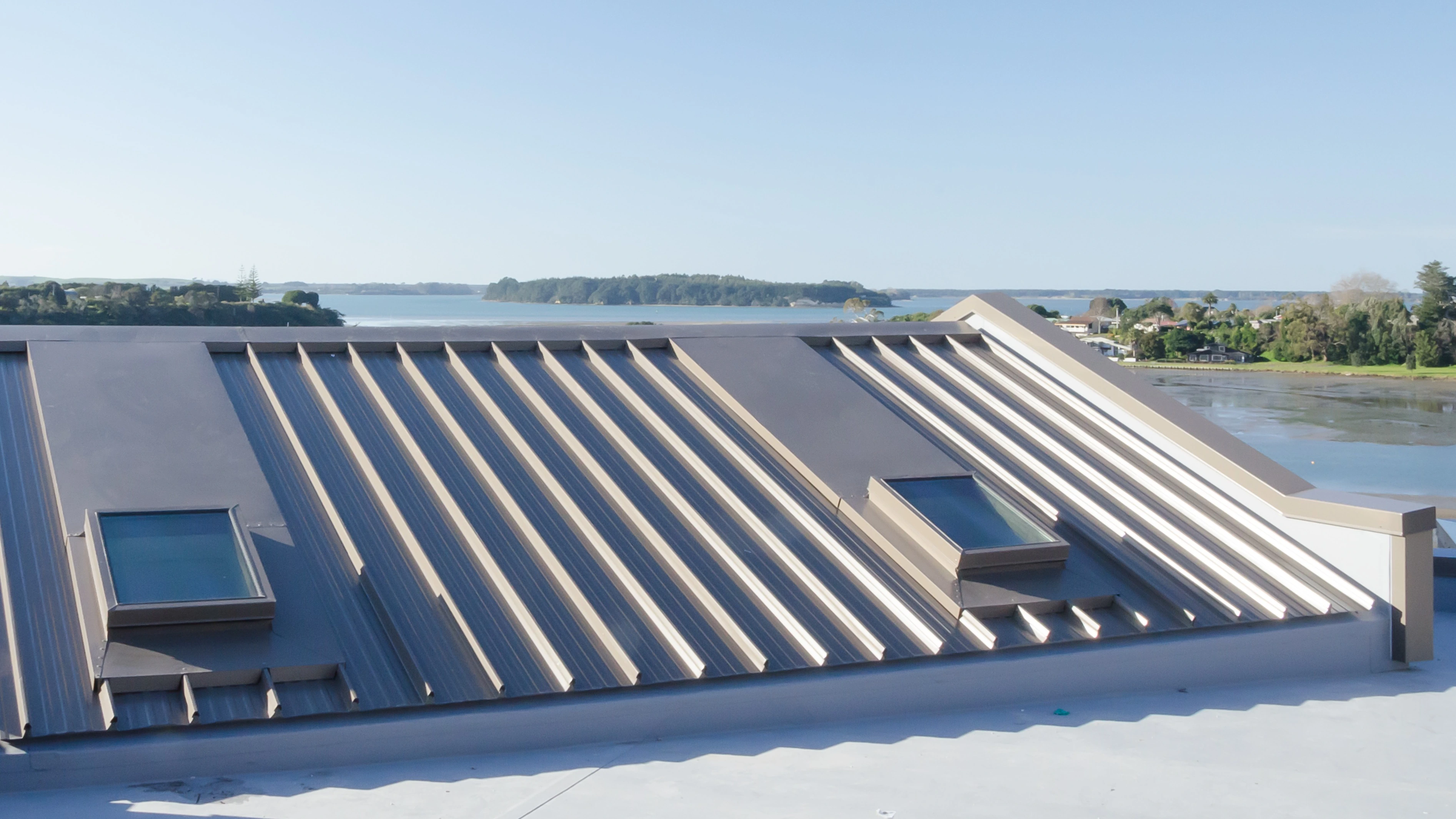 An aerial view of a house roof after re roofing work. In the distance is water and a little island.