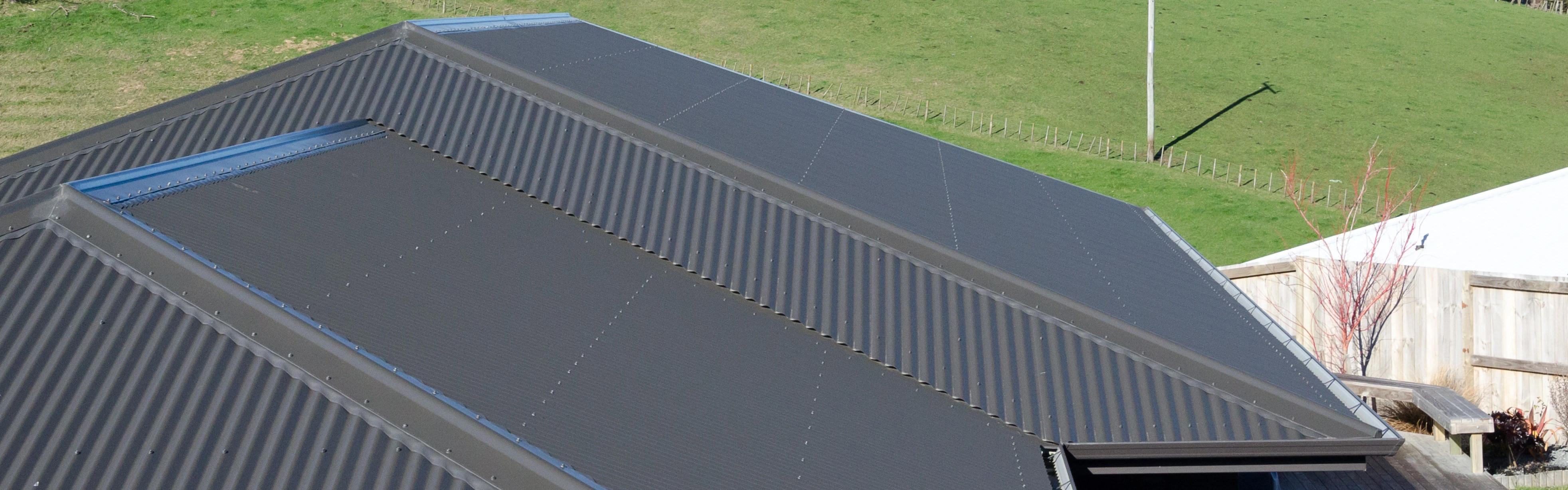 An aerial view of a house roof on a new home, with a field in the background