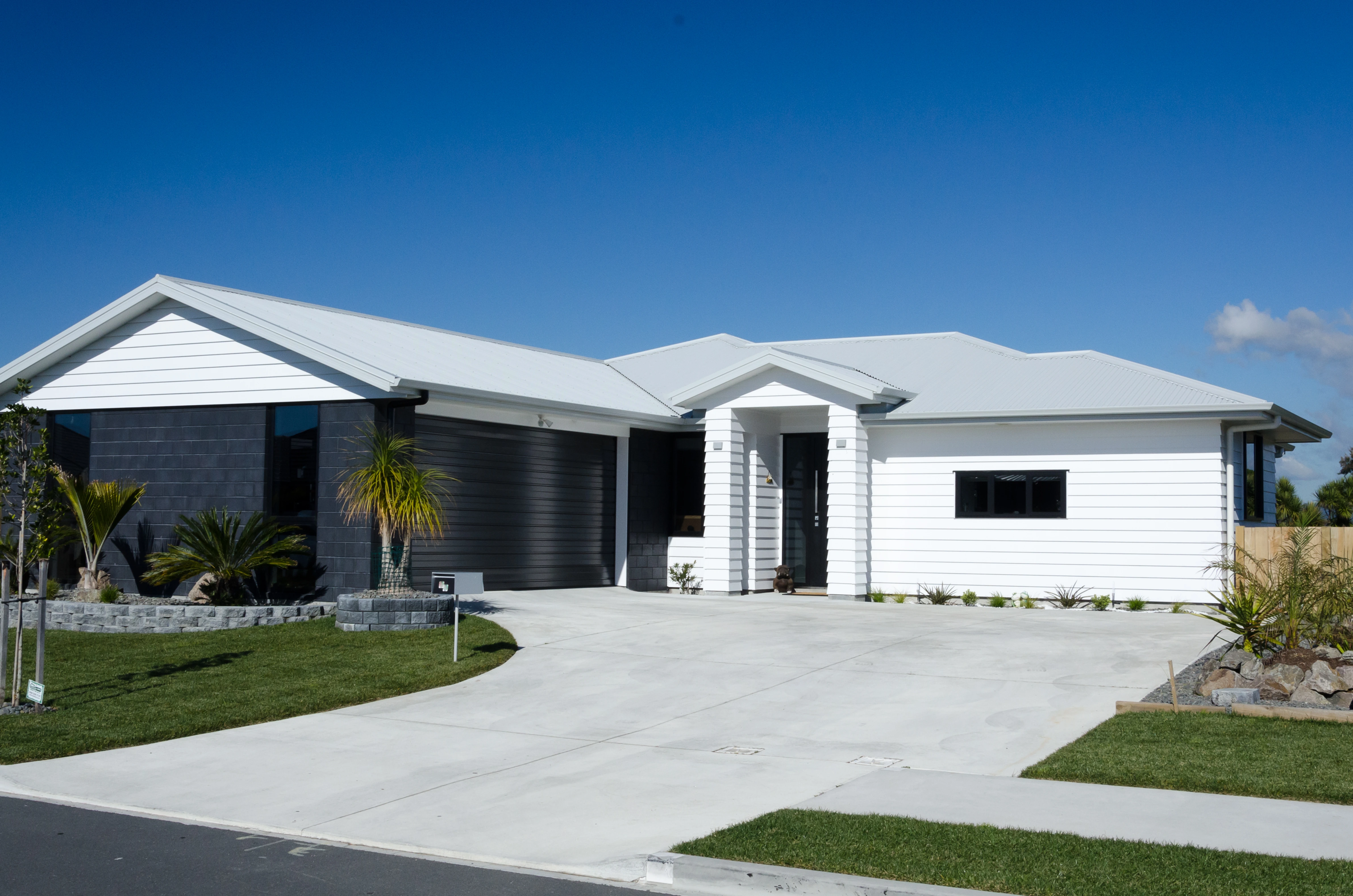 A large home set back from the road, with a wide driveway, front garden, and a new roof