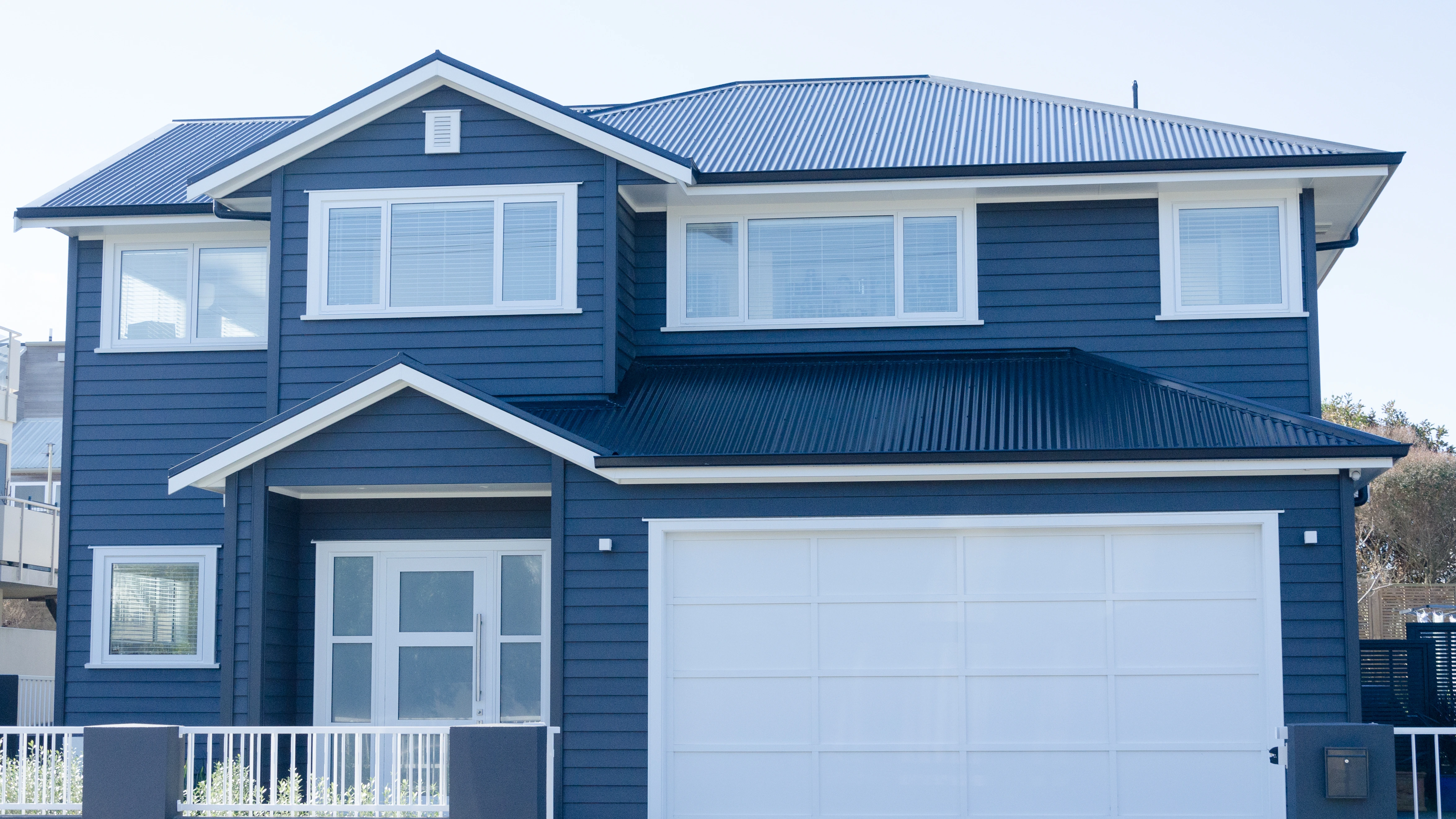 Two storey house with white garage and windows and brand new roof